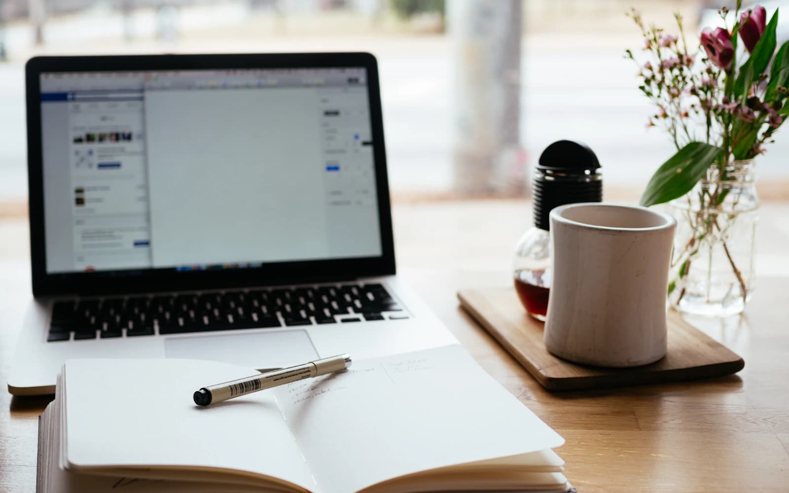 Laptop and open notebook prepared for technical writing